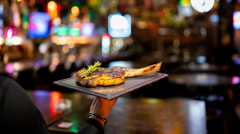 Waiter holding a tomahawk steak in a restaurant