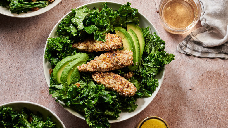 Bowl of kale and avocado salad with almond-crusted chicken