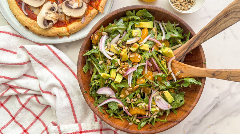 Bowl of arugula salad with avocado, red onion, and mandarins