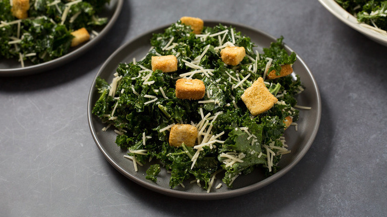 Plate of kale Caesar salad with croutons and shredded cheese