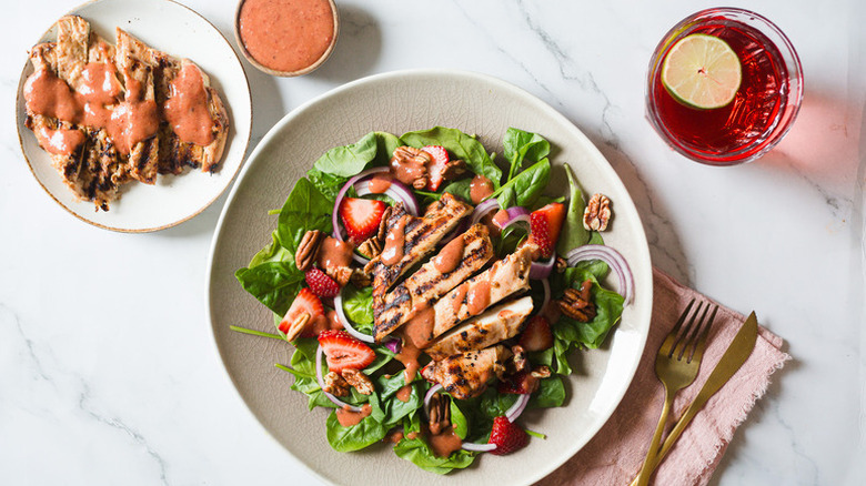 Chicken, strawberry, and spinach salad on plate, drizzled with strawberry balsamic dressing