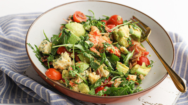 Arugula, avocado, and lobster salad in bowl with fork