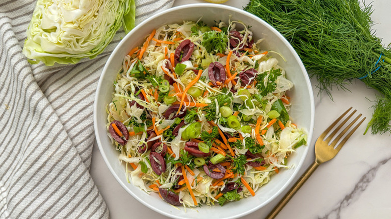 Bowl of shredded cabbage and carrot salad with black olives