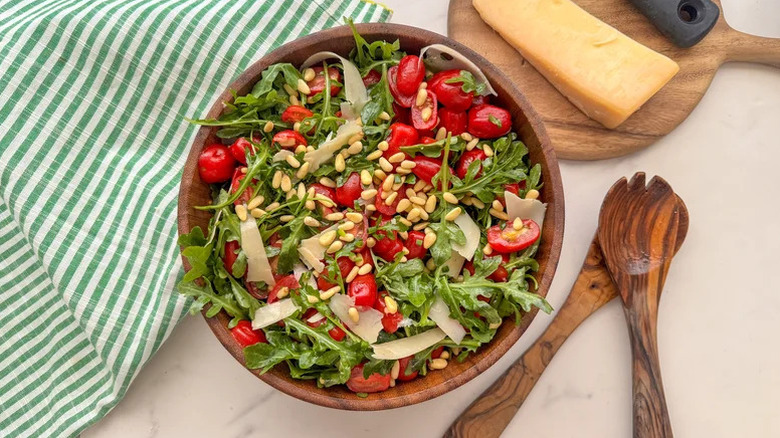 Arugula and tomato salad in wooden bowl