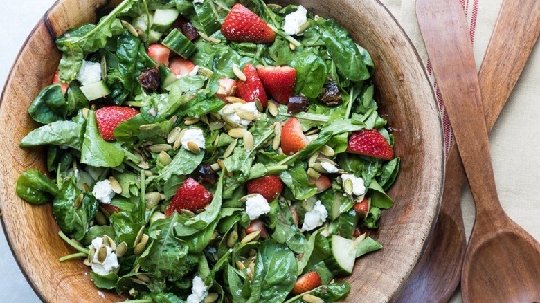 Strawberry and arugula salad in wooden bowl