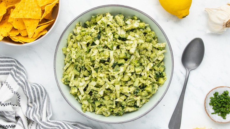 Bowl of green goddess salad next to bowl of tortilla chips