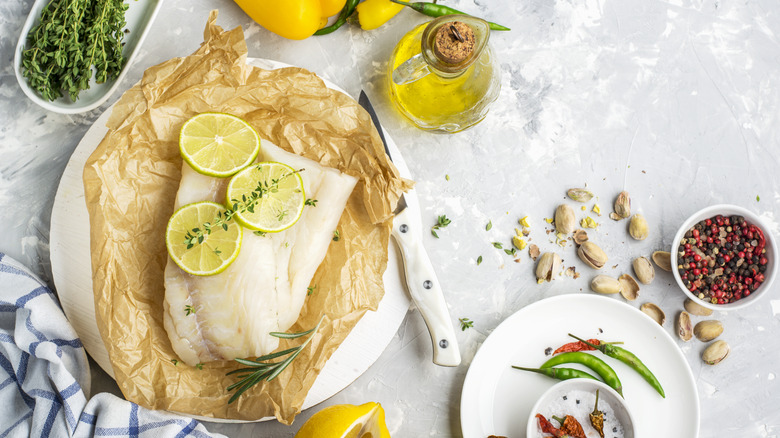 Cod filets withe lemon slices on parchment paper