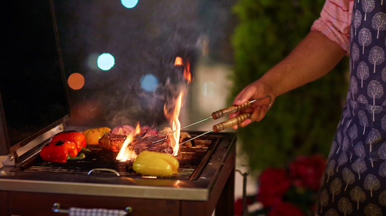 pitmaster managing the flames on an open grill
