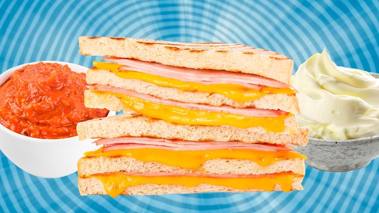 Grilled cheese in between bowls of marinara sauce and mayo against a blue spiral background