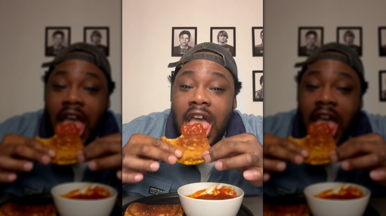 Man eating grilled cheese with marinara sauce