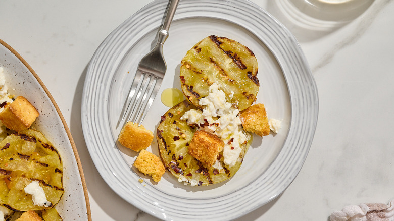 grilled green tomatoes on a plate with croutons and cheese