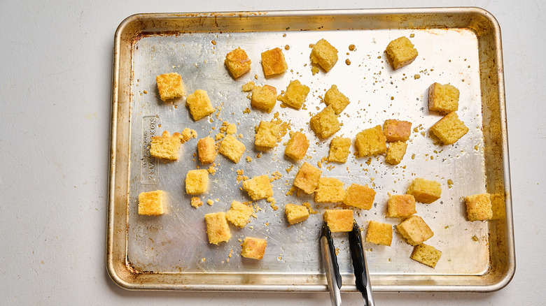 flipping cornbread cubes on a sheet tray