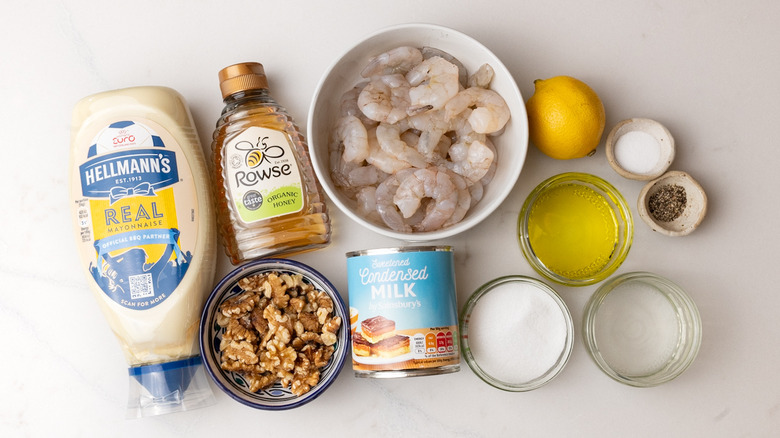 bowl of raw shrimp, mayonnaise, honey, condensed milk, bowl of walnuts, and other grilled honey walnut shrimp ingredients laid out