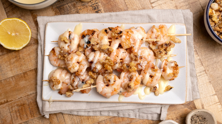 skewers of grilled honey walnut shrimp piled on a plate