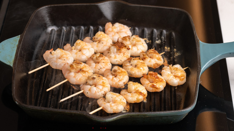 shrimp skewers cooking in griddle pan