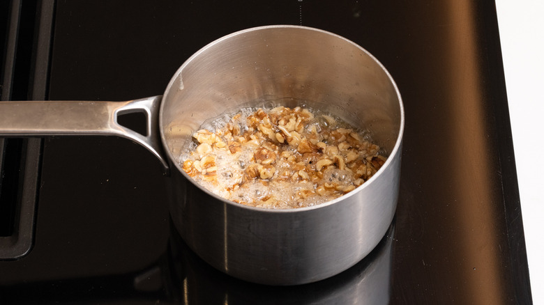 walnuts and sugar mixture cooking in saucepan on the stove
