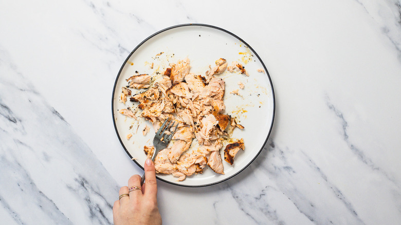 Flaking salmon into pieces with a fork