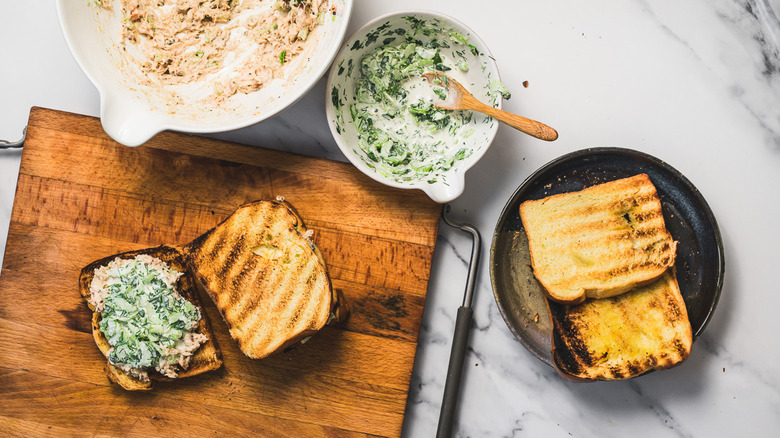 Salmon salad sandwich with bowls of ingredients