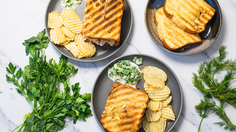 Salmon salad sandwiches on plates with chips