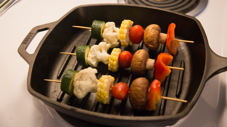 three veggie skewers cooking in pan on the stove