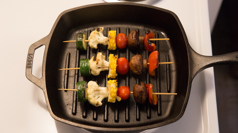 three veggie skewers cooking in pan on the stove