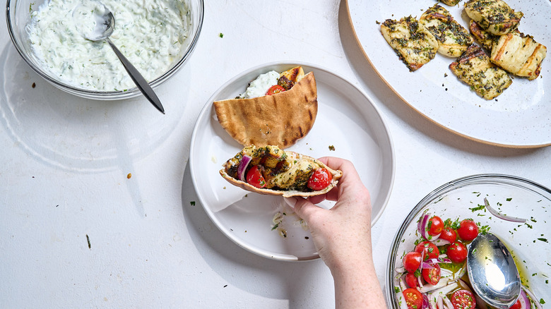 stuffing pita pockets with tomato salad and halloumi