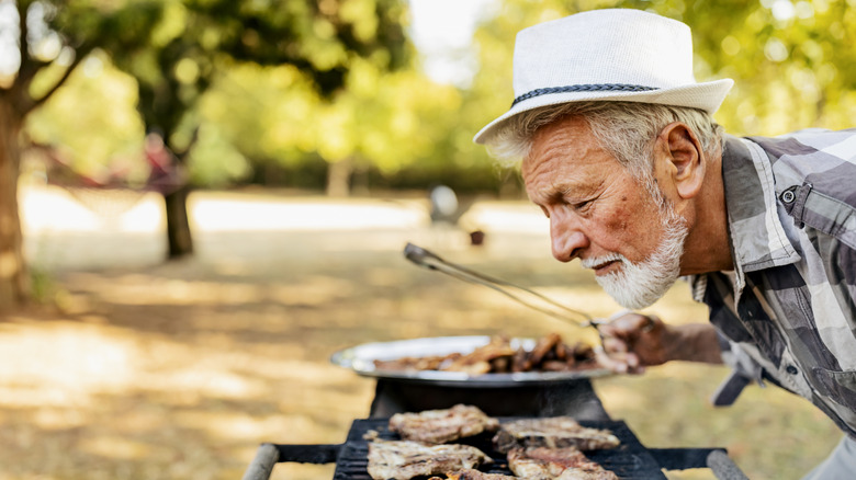 man smelling food from bbq grill