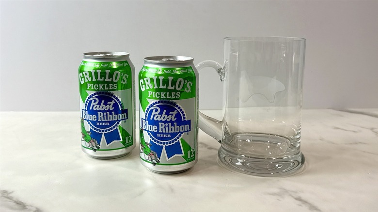 two cans of Pabst blue ribbon Grillo's pickle beer and a glass mug