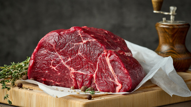 raw beef meat with herbs and spices on wooden cutting board