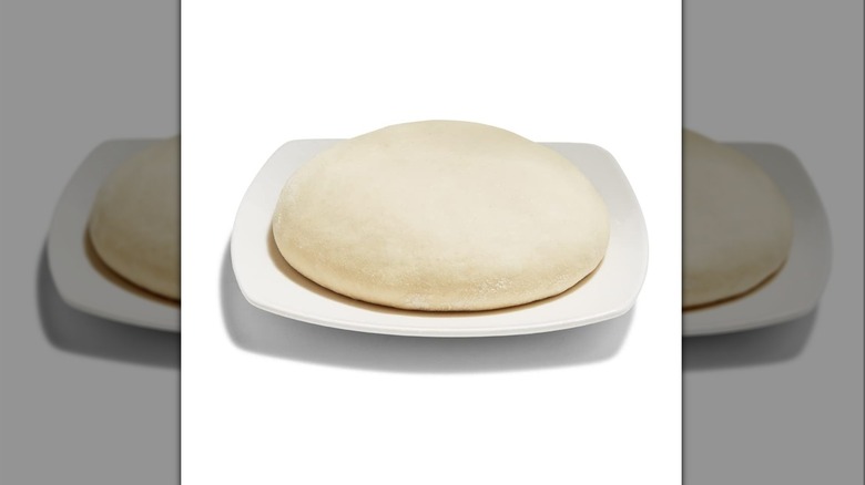 Ball of Whole Foods plain pizza dough on white square dish