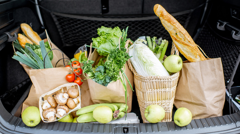 Bags of groceries with prodice and bread in trunk of car