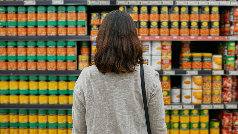 person looking at canned section in grocery store