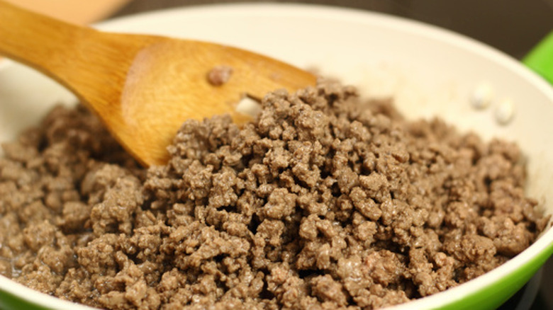 Person mixing beef with a spatula in a pan