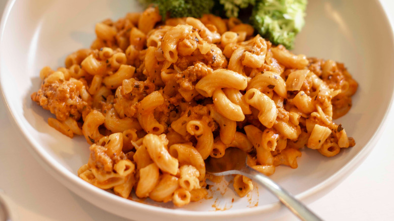 Beef macaroni noodles in a white bowl with broccoli