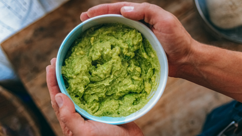 Person holding a bowl of guacamole