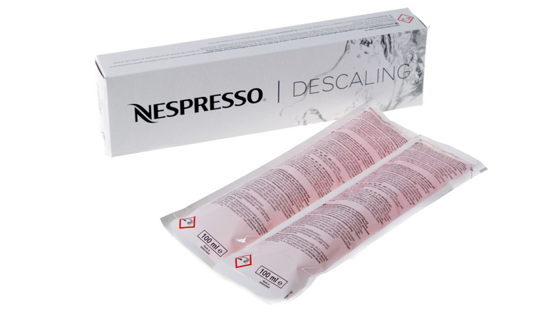 Two Nespresso descaling packs sit next to a Descaling Kit box.