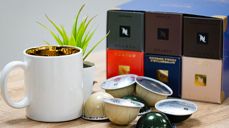 Nespresso pods sit next to a cup of coffee.
