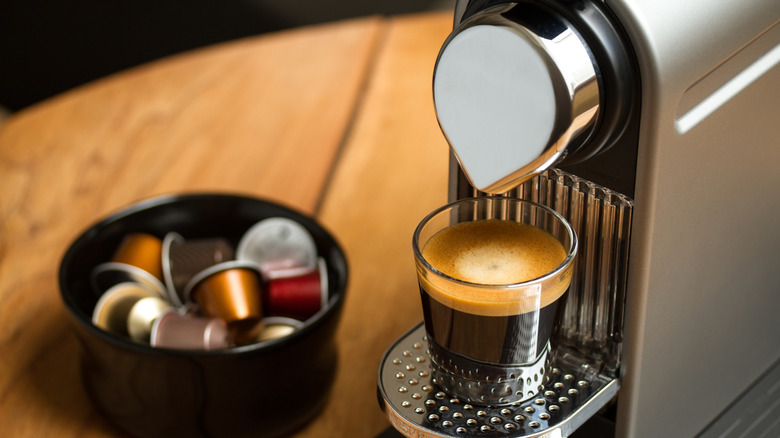 A Nespresso machine sits next to a container of pods.