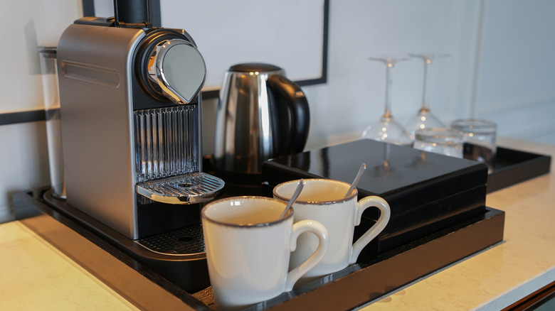 Two empty coffee cups sit in front of a Nespresso machine.