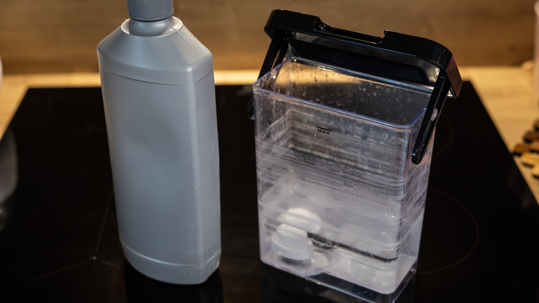 A coffee machine water canister has limescale on it.