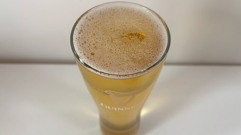 Top-down shot of pint of Guinness Legends Lager in glass on white table