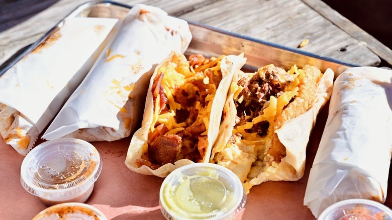 Brisket tacos and cups of sauce on a tray from The Pit Room