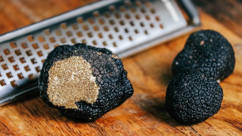 black truffles on a wooden board with a microplane