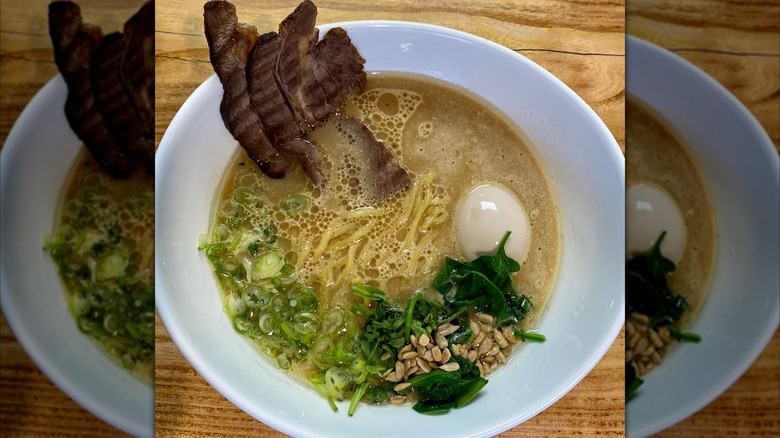 A white bowl of ramen with bison meat on brown table, mirrored image