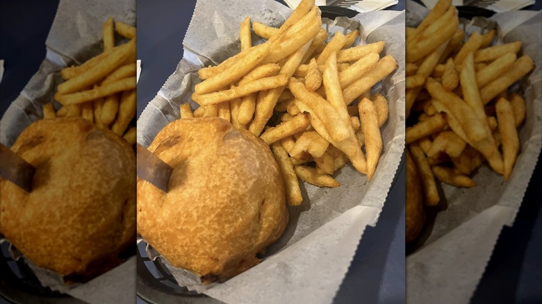 Triple D deep fried burger with fries on paper in plastic basket
