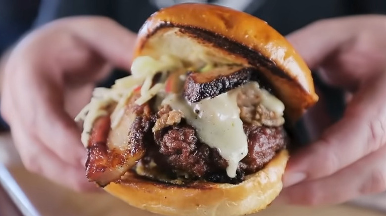 Two hands hold the Texas Nail brisket sandwich from Slow Bone BBQ in Dallas, Texas