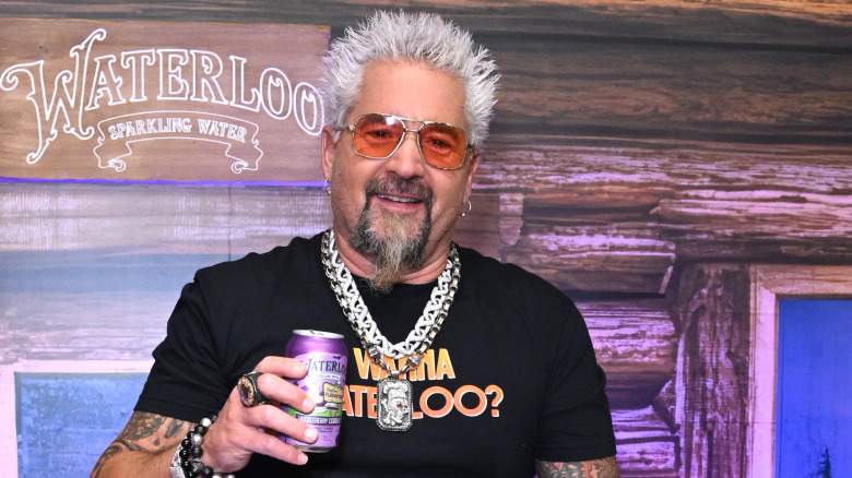 Guy Fieri holding soda can with red glasses and big silver chain