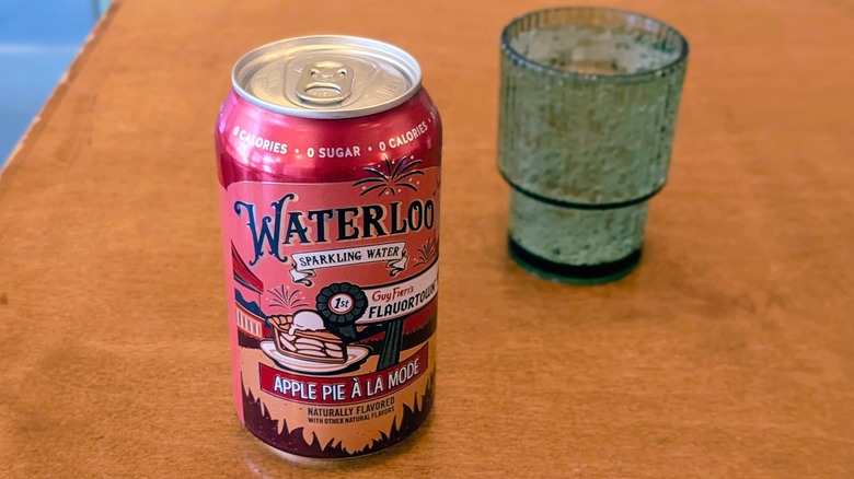 A can of Apple Pie à la Mode Waterloo sparkling water and a palstic cup on a wood table