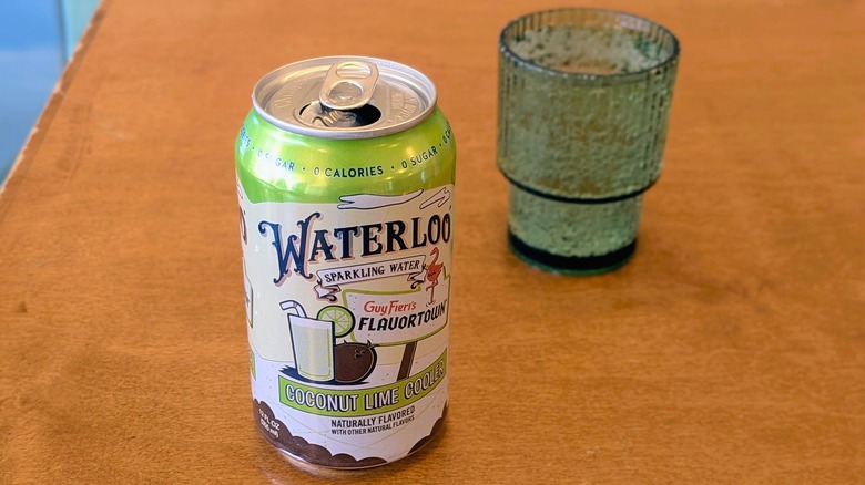 A can of Coconut Lime Cooler Waterloo sparkling water and a palstic cup on a wood table
