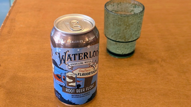 A can of Root Beer Float Waterloo sparkling water and a palstic cup on a wood table